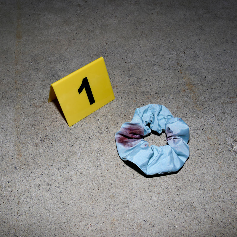 A bloody scrunchie on concrete next to an evidence placard