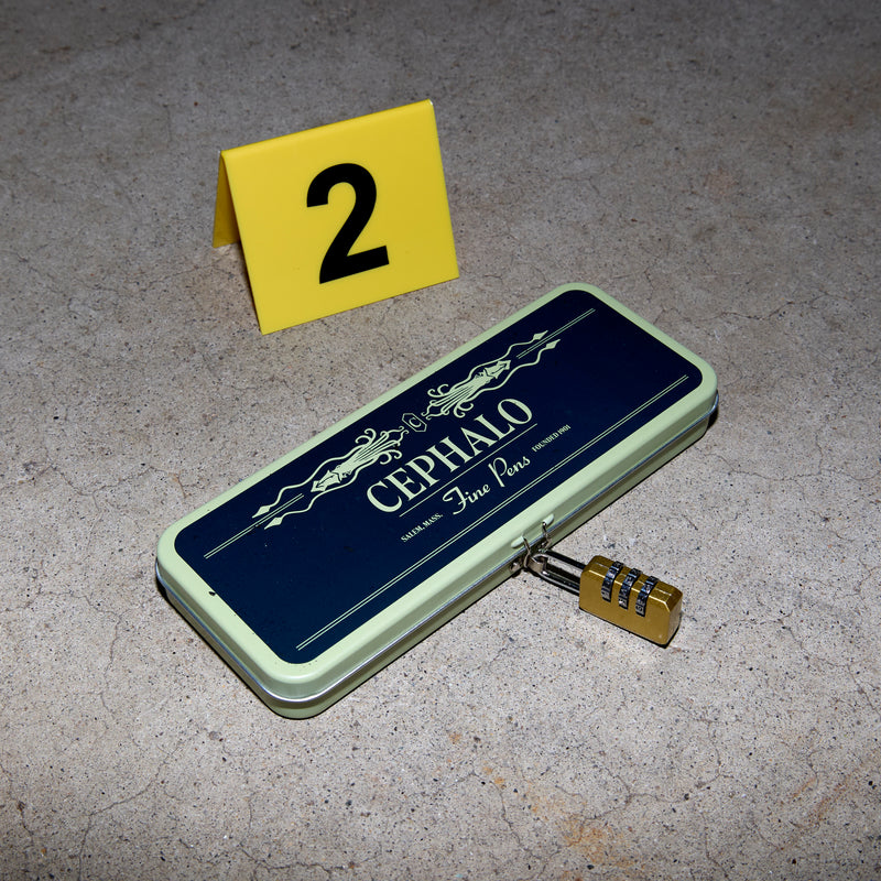 A locked long rectangular tin on the concrete with an evidence placard