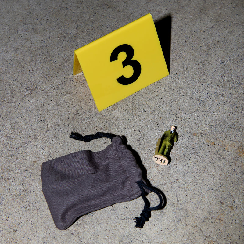 A small figure with a small cloth bag on concrete and an evidence placard